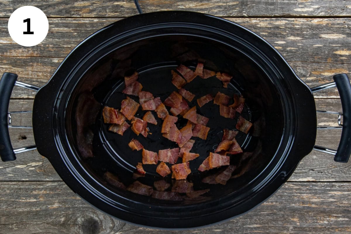 Cooked bacon and bacon grease in the bottom of the slow cooker.