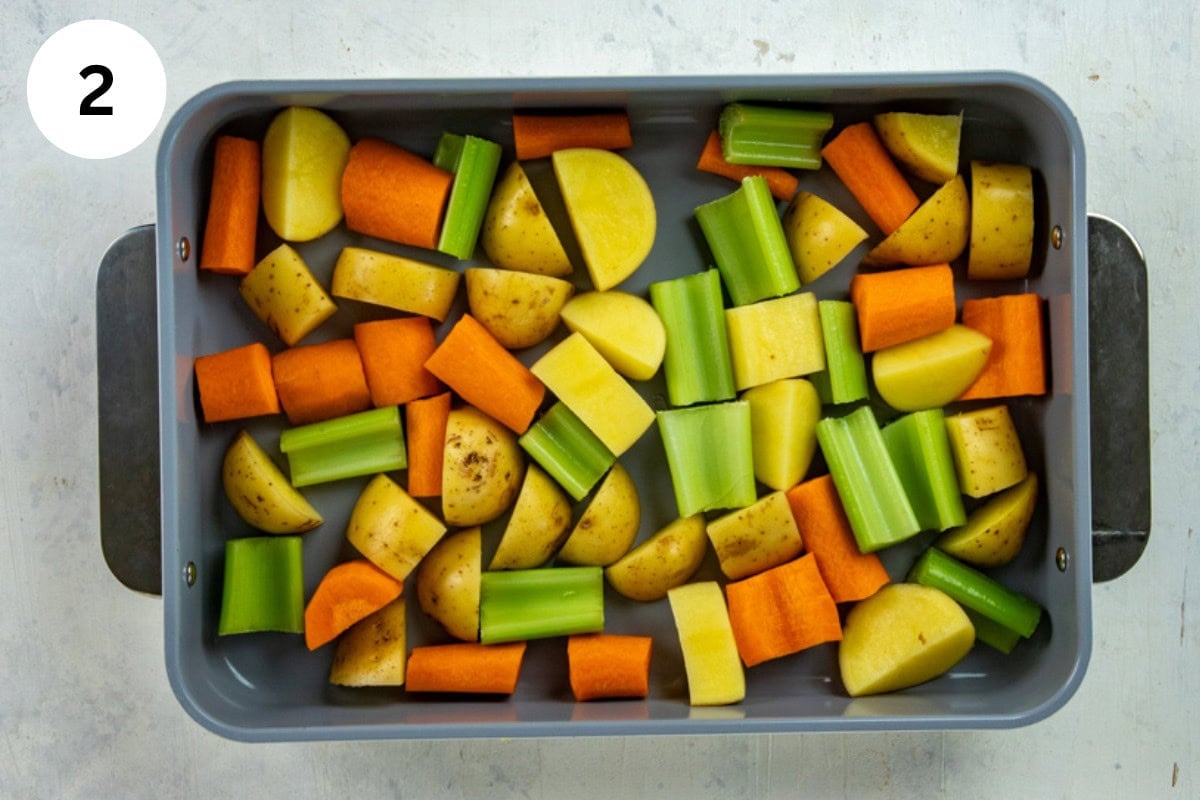 Chopped carrots, potatoes, and celery in a roasting pan.