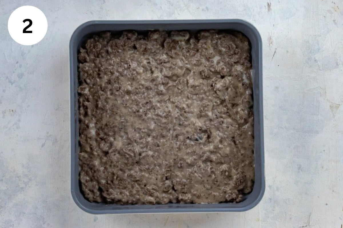 Cream of mushroom soup, milk, and seasonings mixed with the ground beef and added to a square baking pan.
